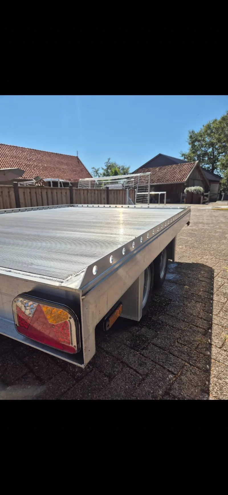 Aluminium laadvloer op een driewielige aanhanger buiten bij een woonhuis
