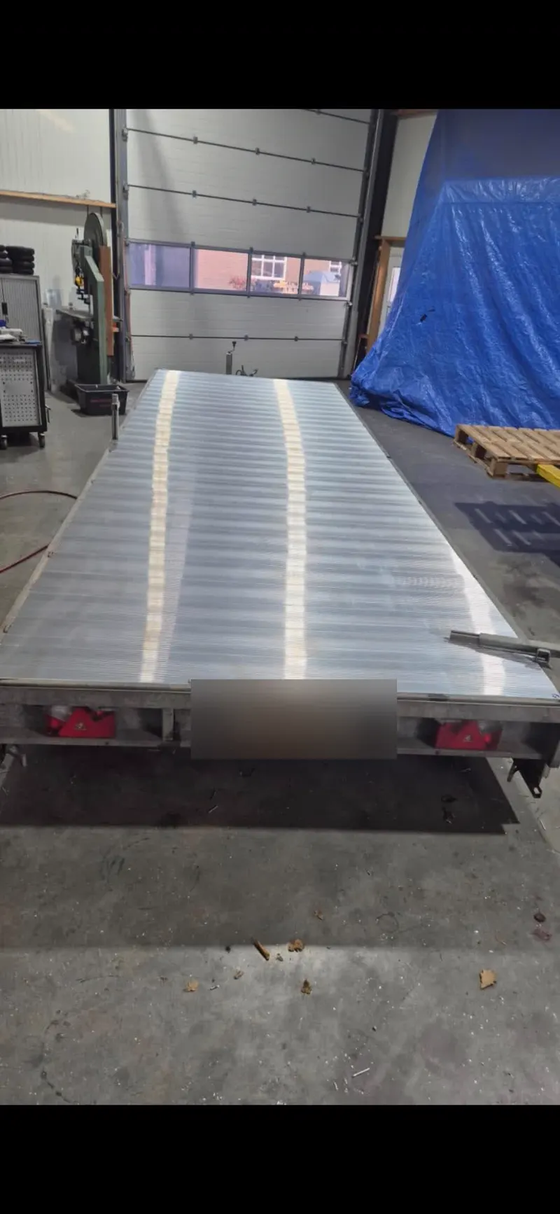 Aluminium laadvloer op een autotransporter-aanhanger in de werkplaats, kenteken afgeschermd