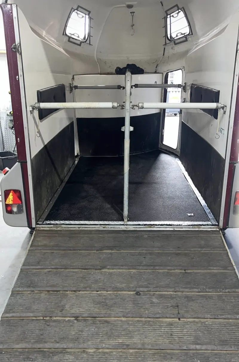 Interieur van een paardentrailer met verstelbare scheidingsstang en rubbermat
