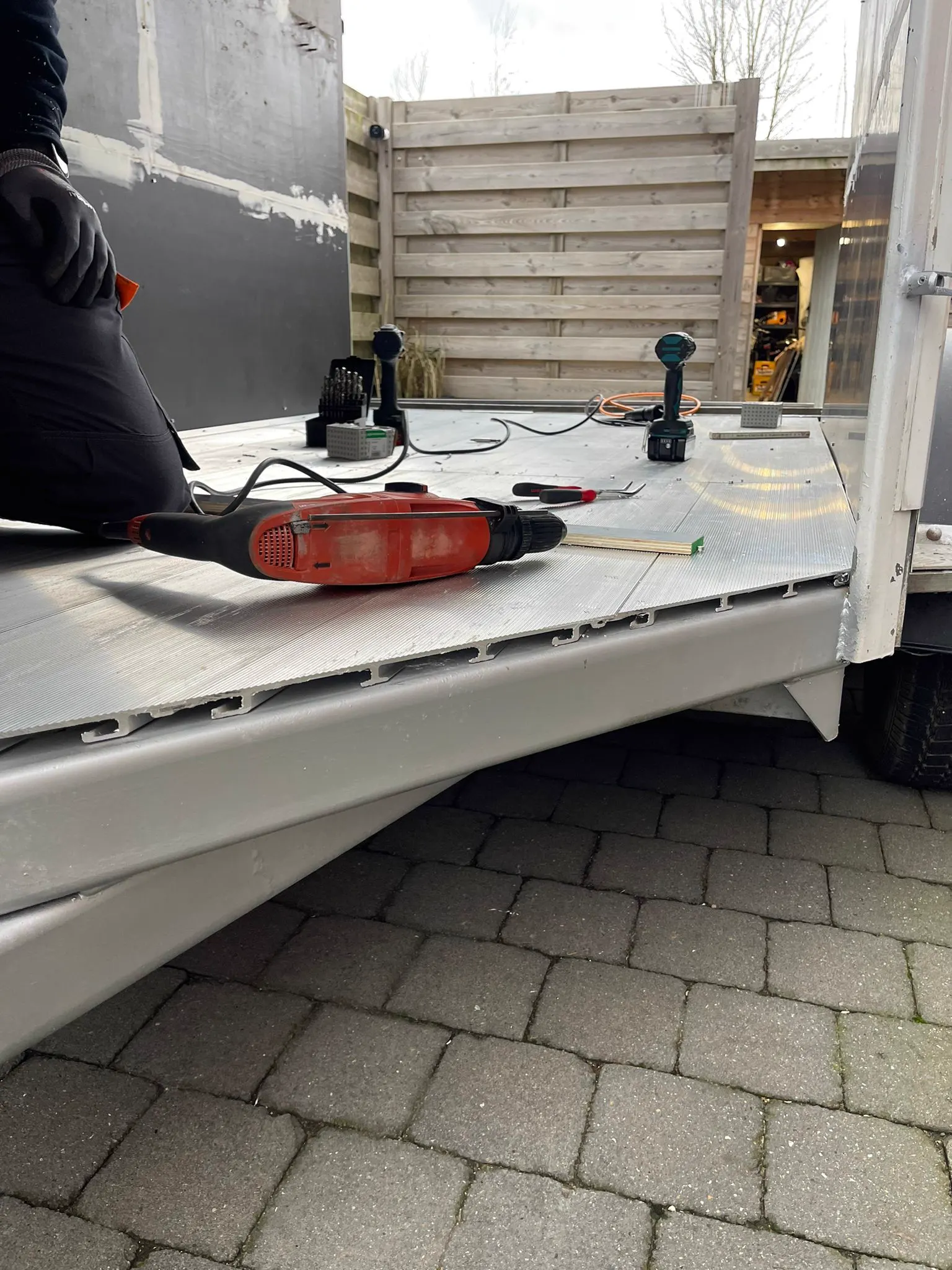 Monteur boort de aluminium laadvloer vast op een oplegger